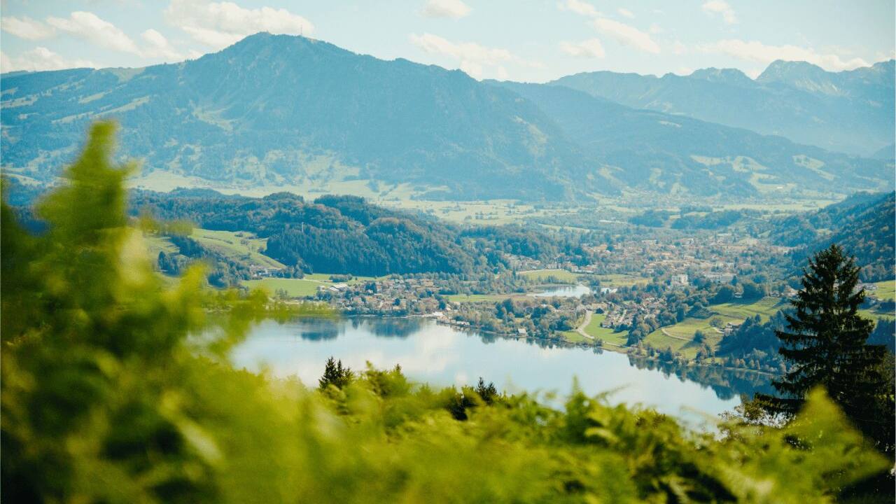 Blick von oben auf den Großen Alpsee bei Immenstadt, dahinter der Grünten und die Allgäuer Alpen