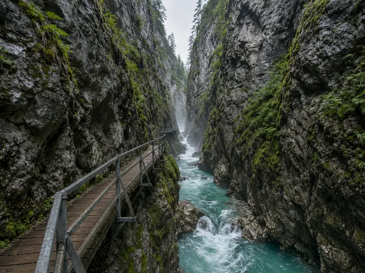 Holzsteg an der Felswand der Breitachklamm bei Oberstdorf, tief unten rauscht das grüne Wasser der Breitach zwischen moosigen Felsen