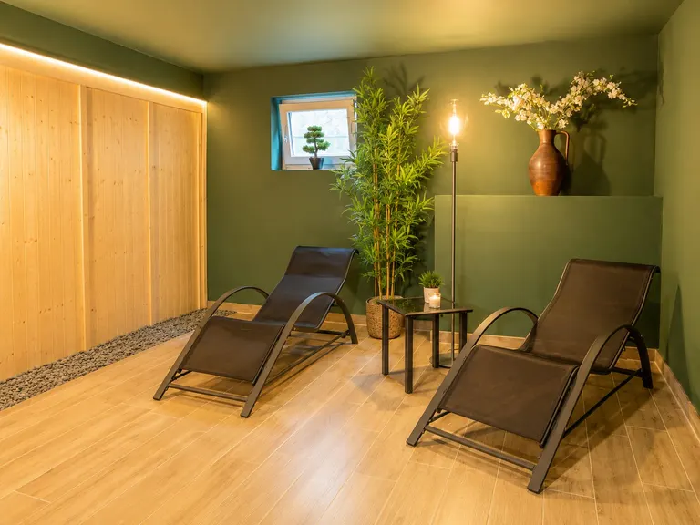 Ruheraum mit Liegen und Holzsauna in einer Ferienwohnung mit Sauna im Allgäu