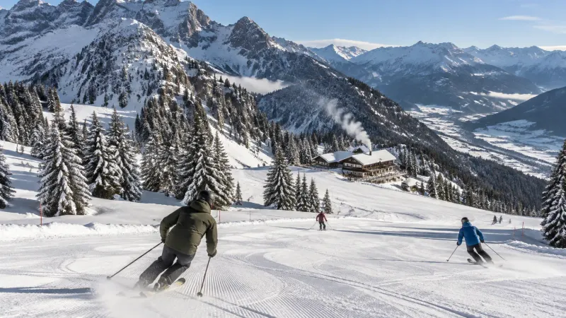 Skifahrer auf einer frisch präparierten Piste im Allgäu, verschneite Tannen und Gipfel unter blauem Himmel