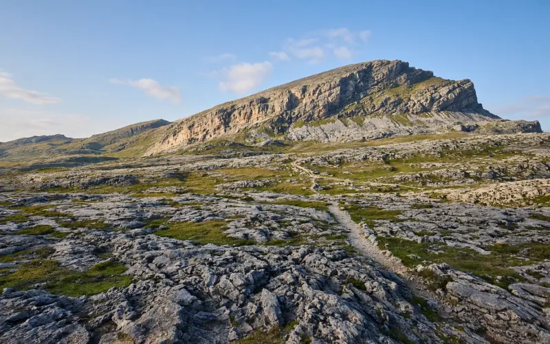 Zerklüftete Karstfelsen und grüne Mulden auf dem Gottesackerplateau im Kleinwalsertal, dahinter die schräg aufragende Felsplatte des Hohen Ifen im Spätsommerlicht
